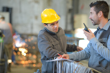two builders in helmets working with walkie talkie