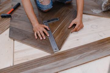 Man laying parquet flooring - closeup on male hands. worker joining parquet floor