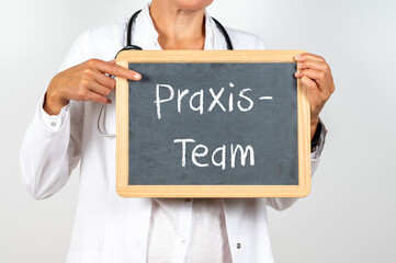 Hausärztin mit einer Tafel auf der Praxis Team steht