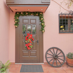 Fototapeta na wymiar stylish family house entrance brown door on pink wall, Christmas decorated