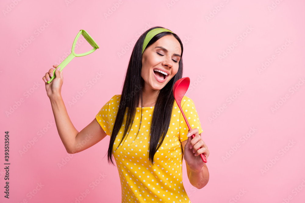 Sticker Photo of joyful young housemaid wear yellow dotted t-shirt pin-up sing spoon isolated on pink color background