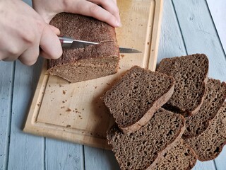 women's hands cut into rye homemade bread made on sourdough