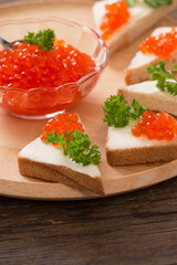 toast with red caviar on  wooden tray