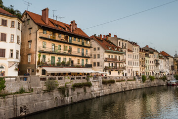The canalized banks of on the Ljubljanica river in the slovenian capital city Ljubljana with the old houses and restaurants on sunny day in summer with clouds