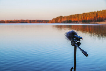 Portable recorder stands on a tripod on the lake shore. Recording sounds of nature © Mariya Fedorova