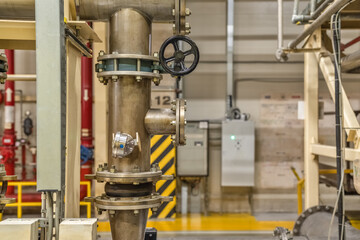 Black valve on the background of pipes in the production room.