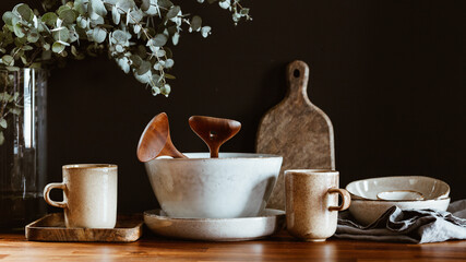 Set of kitchen ceramic tableware and wooden cutting boards on a table. Eco style home still life.