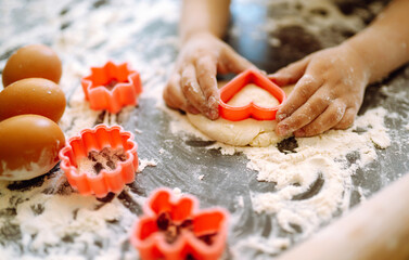 Kids hands cutting out shapes and making cookies. Making biscuits for christmas decorations. Children's art project, a craft for children.