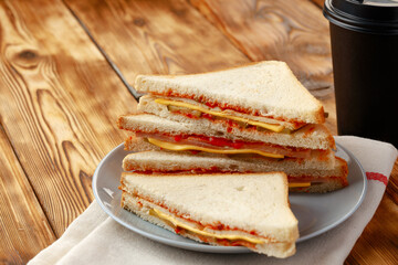 Toast sandwich and cup of coffee on napkin on wooden table