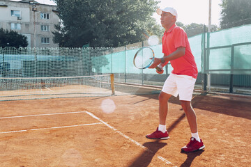 Middle-aged man playing tennis on outdoor tennis filed