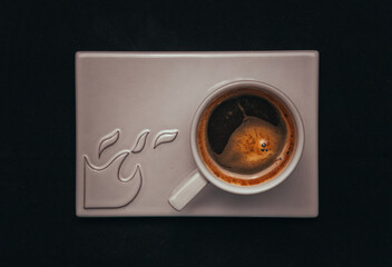 Closeup of a cup of black coffee with coffee beans on  the side