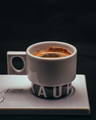 Closeup of a cup of black coffee with coffee beans on  the side