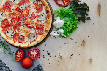 flat pizza, top photo, ingredients and kitchen utensils laid out around. Wooden background and towel