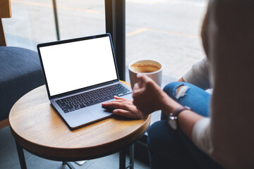 Fototapeta premium Mockup image of a hand touching on laptop computer touchpad with blank white desktop screen while drinking coffee