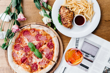 pizza dishes, french fries, grilled chicken and aperol on the table