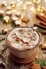 Festive hot chocolate with creamy foam and marshmallow stars sprinkled with aromatic cinnamon close up view
