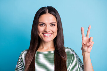 Portrait of satisfied woman arm fingers show v-sign toothy smile wear white green isolated on blue color background
