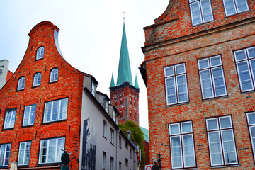 Fototapeta premium Old brick buildings in Lubeck, Germany. St. Peter's Church (St. Petrikirche) in a background.