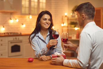 Young loving happy couple looking at each other and clinking glasses with wine