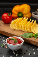 Potato chips and vegetables in composition on black background