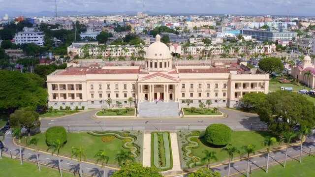 Backward flight with drone in the Presidential Palace of Dominican Republic, beautiful green garden, sunny day