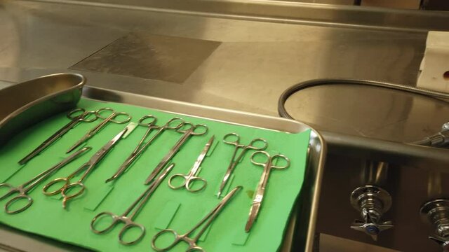 Medium Shot Of Empty Morgue Gurney, Sink And Tray Of Scissors