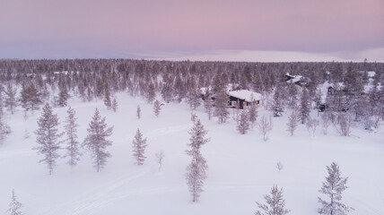 Visit Lapland Holidays. Aerial drone panorama shot of the forest covered in snow winter and the village inside the Arctic Circle. Lapland, Finland. Winter sunrise. Igloos and cabins covered with snow