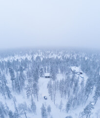 Car approaching the cabin in the woods in Lapland, Arctic circle. Scandinavian winter snowy paradise. Christmas Hollidays. Aerial drone shot of the forest covered in snow winter 
