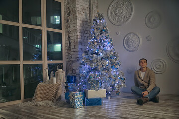 guy decorates the Christmas tree / man model in the New Year's studio