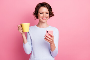 Positive girl use smartphone read social media news hold mug beverage isolated pastel color...