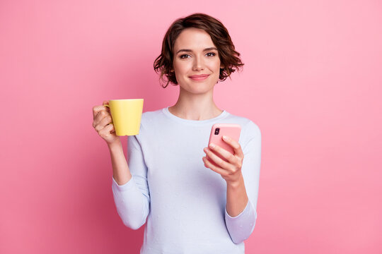 Portrait of positive blogger girl relax use smartphone hold latte cup wear sweater isolated over pastel color background - Powered by Adobe