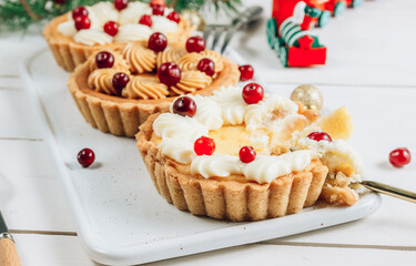 Mini cheesecake with cranberries on a white wooden table with Christmas decorations. Selective focus