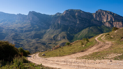Obraz premium landscape in the mountains, field mountain road leading to a mountain village, against the background of mountains