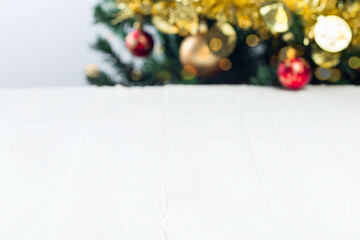 Empty white wooden background with blur Christmas tree, balls and glitter, horizontal, copy space