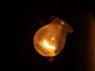 Old bulb lamp glowing in the dark. Beautiful dusty vintage lights decor on the wall. Retro style electric yellow bulbs decoration. Idea and teamwork concept