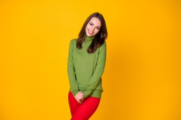 Fototapeta premium Portrait of attractive shy cheery girl wearing cosy clothing posing isolated over bright yellow color background