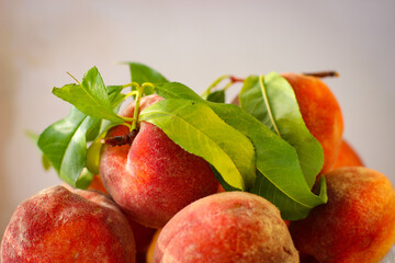 Few ripe peaches with green leaves on a white background with a copy space