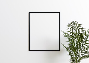 Vertical 8x10 Black Frame mockup. Vertical Black frame on a white wall with plant leaves.