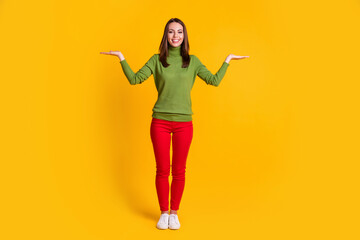 Fototapeta na wymiar Full length body size view of pretty cheerful girl holding on palms copy space isolated over bright yellow color background