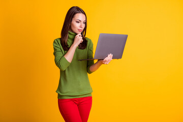 Photo of attractive lady hold notebook look screen arm on chin wear green sweater red pants isolated yellow color background