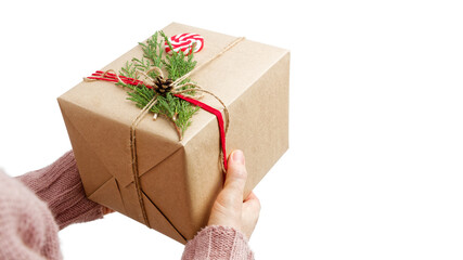 Female hands holding gift box wrapped in kraft paper and tied with twine. Isolated on white...