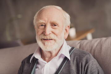 Photo of positive handsome old man smiling sitting sofa inside indoors flat home house
