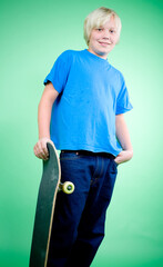 Studio photo of 10 year old caucasian boy with blond hair with skateboard looking at camera on colorful green background. © Stockis