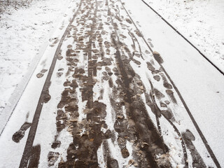 Footprints of people and baby carriage on fresh snow on the sidewalk in the city
