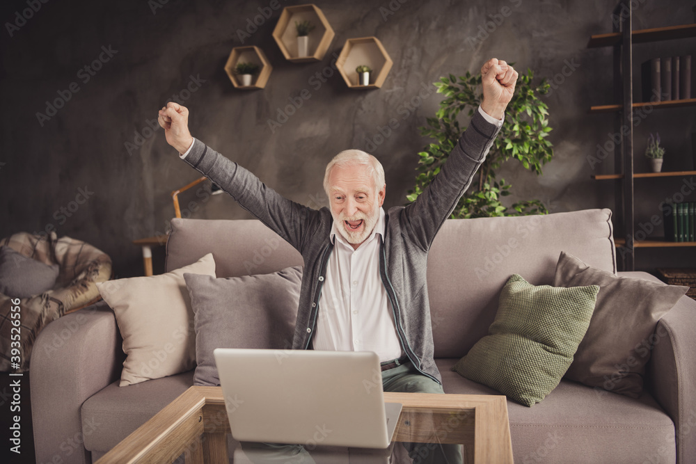 Sticker photo of excited old man dressed white shirt sitting sofa looking modern device hands arms fists ind