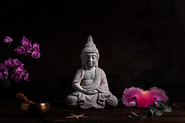 Close up of a statue of Buddha with singing bowl and prayer beads (mala) for chanting mantras as...