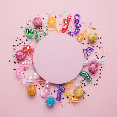 Party celebration frame made with vibrant, multi colored confetti on pastel pink background. Christmas party or birthday celebration invitation card concept. Flat lay.