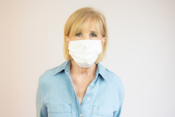 Senior woman in medical mask isolated on yellow background looking at camera protecting from flu epidemic and pollution - coronavirus pandemic, prevention, protection concept