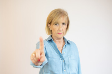 Old lady showing finger up gesture, smiling on white background