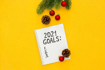 Naklejka premium New year goals list. Christmas decorations and notebook on yellow